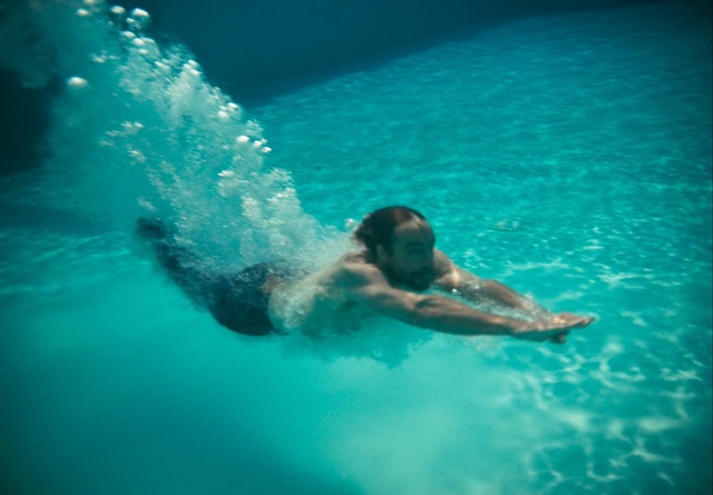 Video Reference N1: Water, Blue, Green, Aqua, Wave, Turquoise, Leisure, Fun, Recreation, Sky, Sport, Swimming, Riding, Pool, Ocean, Man, Board, Large, Body, Game, Surfing, Young, Bear, Frisbee, Purple, Clear, Laying, Flying, Water sport, Swimming pool, Person