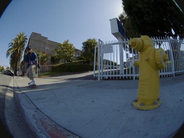 Video Reference N2: Fisheye lens, Yellow, Asphalt, Photography, Road surface, Sky, Skateboarding, Tree, Recreation, World, Outdoor, Person, Man, Riding, Hydrant, Park, Young, Ramp, Boy, Building, Side, Board, Sidewalk, Jumping, Doing, Trick, Fire, Shirt, Air, Street, Standing, Skating, Fire hydrant, Statue, Playground, Outdoor object