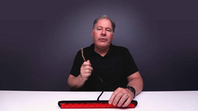 Video Reference N6: Arm, Finger, Public speaking, Speech, Hand, Electronic instrument, Thumb, Person, Indoor, Man, Sitting, Table, Laptop, Computer, Front, Holding, Looking, Young, Using, Black, Screen, Shirt, Red, Cake, Desk, Large, Standing, Game, Human face, Clothing