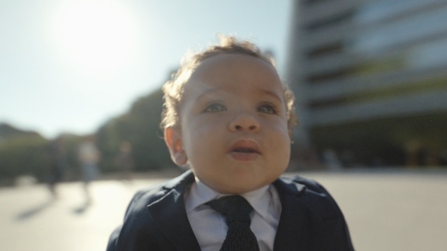 Video Reference N0: Face, Child, Facial expression, Head, Nose, Cheek, Skin, Male, Chin, Standing, Person, Necktie, Wearing, Young, Boy, Smiling, Small, Suit, Little, Front, Shirt, Man, Dressed, Posing, White, Holding, Red, Water, Blue, Human face, Toddler, Baby, Clothing