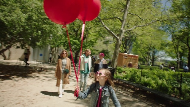 Video Reference N2: Balloon, Party supply, Fun, Tree, Leisure, Outdoor, Red, Walking, Carrying, Street, Holding, Riding, Man, Woman, Wearing, Snow, Water, Umbrella, Hat, Standing, Large, Track, Skiing, Ground, Clothing, Person, Girl