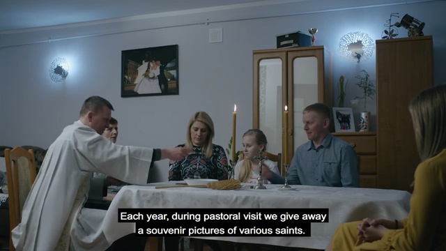 Video Reference N1: Event, Room, Photo caption, Person, Indoor, Man, Looking, People, Front, Photo, Sitting, Woman, Standing, Posing, Table, Cake, Holding, Group, Large, Living, Wine, White, Train, Human face, Candle, Text, Clothing