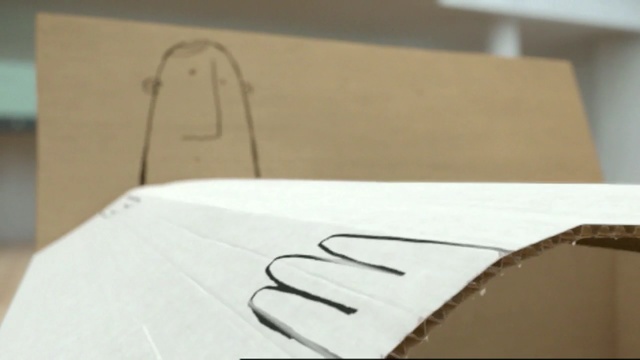 Video Reference N6: cardboard, design, font, material, paper, table, wood, product, angle, Person