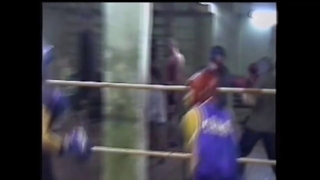 Video Reference N18: Boxing ring, Professional wrestling, Sport venue, Sports, Contact sport, Wrestling, Striking combat sports, Boxing equipment, Boxing, Wrestler, Man, Blurry, Photo, Holding, Standing, Young, Game, Woman, Room, Mirror, Teeth, Kitchen, White, Display, Refrigerator, Playing, Ball, Phone