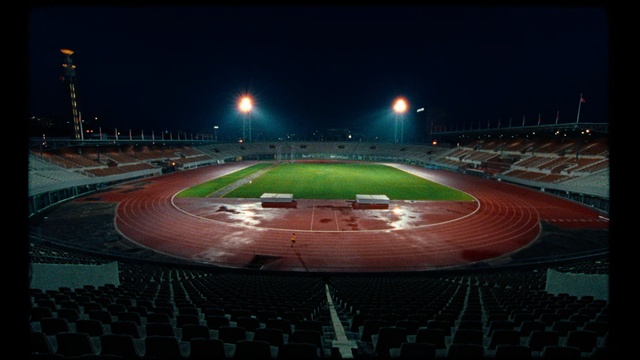 Video Reference N1: Sport venue, Stadium, Arena, Night, Atmosphere, Race track, Sky, Soccer-specific stadium, Sports, Competition event, Outdoor, Sitting, Plane, Light, Large, Runway, Red, Table, Green, Lit, Engine, Airplane, Track, White, Water, Tarmac, Parked, Blue, Street, Baseball