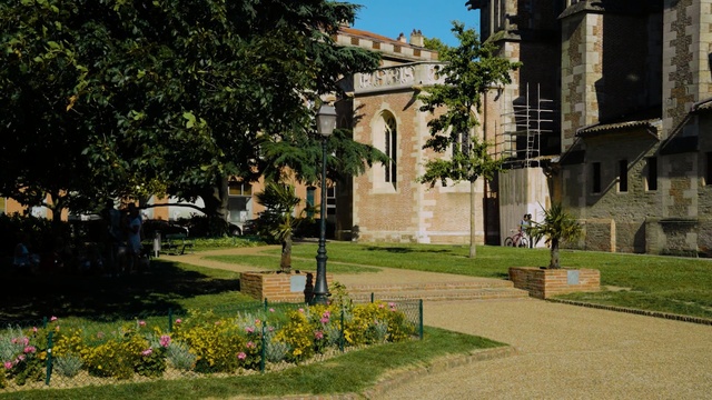 Video Reference N8: tree, estate, plant, grass, neighbourhood, real estate, place of worship, abbey, garden, city, Person