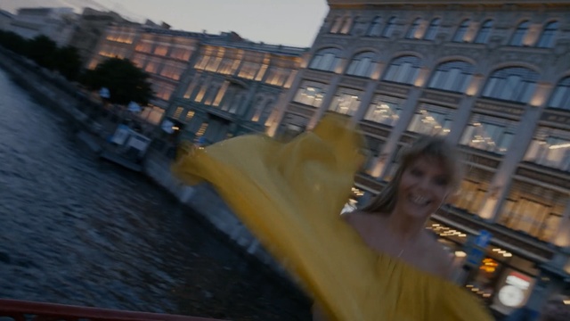 Video Reference N0: Metropolitan area, Architecture, Urban area, Metropolis, Sky, City, Person, Outdoor, Riding, Man, Water, Yellow, Woman, Holding, Young, Girl, Street, Boy, Standing, Table, Large, Phone, River, Bridge, Boat, Train, Board, White, Motorcycle, Human face, Smile