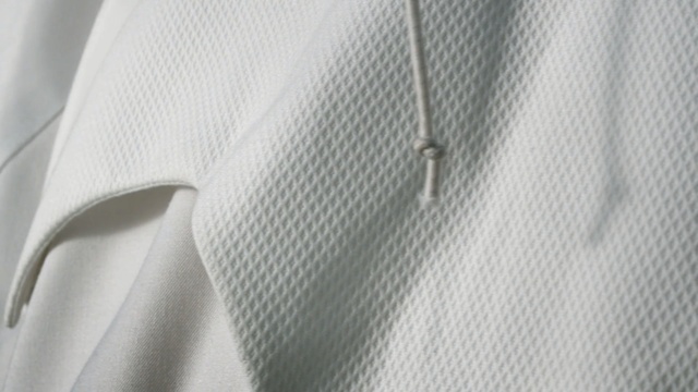 Video Reference N2: white, clothes hanger, shoulder, outerwear, sleeve, textile, line, collar, button, design