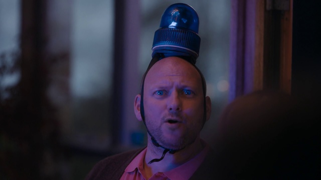 Video Reference N4: Face, Blue, Head, Light, Purple, Forehead, Human, Eye, Fun, Headgear, Person, Indoor, Man, Wearing, Looking, Front, Sitting, Table, Shirt, Young, Close, Standing, Holding, Food, Pink, White, Hat, Cake, Red, Room, Pizza, Human face, Clothing, Fashion accessory