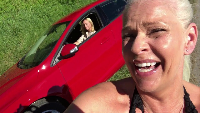 Video Reference N2: Vehicle, Vehicle door, Car, Automotive exterior, Photography, Driving, Automotive window part, Compact car, Smile, Person, Grass, Outdoor, Smiling, Woman, Posing, Red, Wearing, Holding, Man, Front, Camera, Truck, Standing, Glasses, Young, Black, White, Large, Field, Bus, Riding, Human face, Land vehicle, Clothing, Wheel