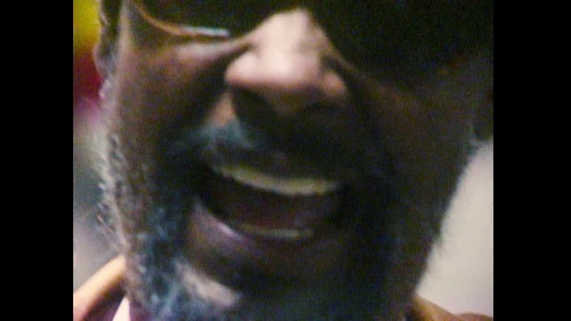 Video Reference N14: Facial hair, Hair, Beard, Face, Nose, Forehead, Black, Facial expression, Chin, Moustache, Person, Indoor, Looking, Front, Man, Glasses, Wearing, Teeth, Sitting, Staring, Camera, Mouth, Cat, Goggles, Smiling, Hat, Shirt, Close, Brushing, Young, Mirror, Standing, Red, Sunglasses, Human face, Text, Spectacles