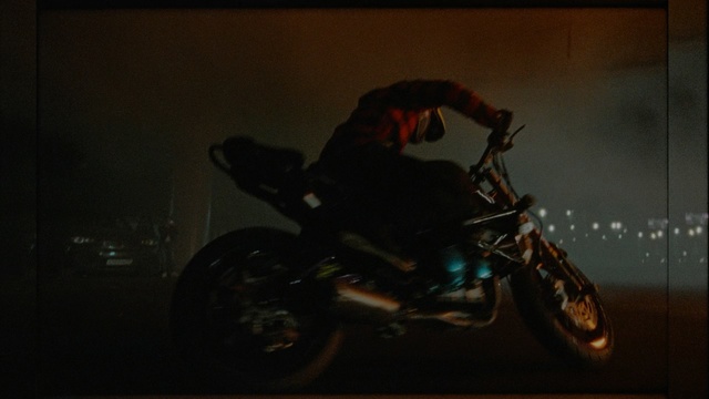 Video Reference N3: motorcycle, darkness, car, vehicle, night, stunt performer, freestyle motocross, screenshot, extreme sport, automotive lighting, Person