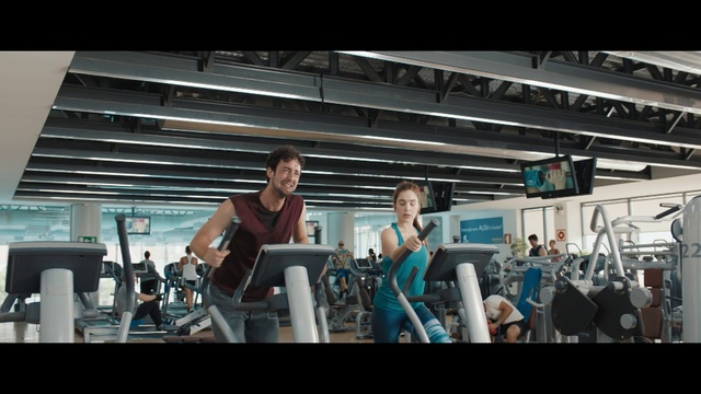 Video Reference N1: Gym, Treadmill, Shoulder, Exercise machine, Exercise equipment, Arm, Physical fitness, Bodybuilding, Sport venue, Room, Indoor, Person, Man, Standing, Table, Woman, Front, People, Group, Young, Kitchen, Holding, Doing, Air, White, Playing, Clothing, Computer
