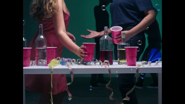 Video Reference N0: Pink, Magenta, Fun, Party supply, Drink, Nail, Liqueur, Party, Alcohol, Distilled beverage, Person, Woman, Indoor, Table, Holding, Front, Standing, Man, Lady, Girl, Sitting, Food, Playing, Computer, Young, Laptop, People, Game, Room, Video, Clothing, Bottle