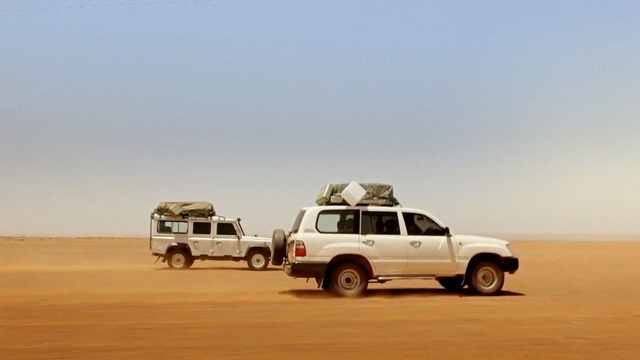 Video Reference N3: white car, desert, motor vehicle, aeolian landform, transport, vehicle, sand, mode of transport, landscape, sahara, off roading, Person