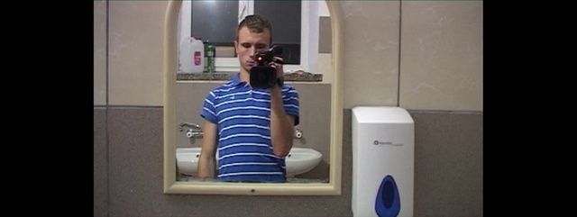 Video Reference N1: Shoulder, Water cooler, Selfie, Restroom, Person, Indoor, Mirror, Front, Man, Standing, Looking, Holding, Open, White, Young, Reflection, Teeth, Shirt, Mouth, Kitchen, Woman, Refrigerator, Wearing, Door, Blue, Phone, Computer, Room, Sink, Brushing, Bathroom, Plumbing fixture, Clothing, Shower, Tap, Bathtub, Home appliance, Kitchen appliance