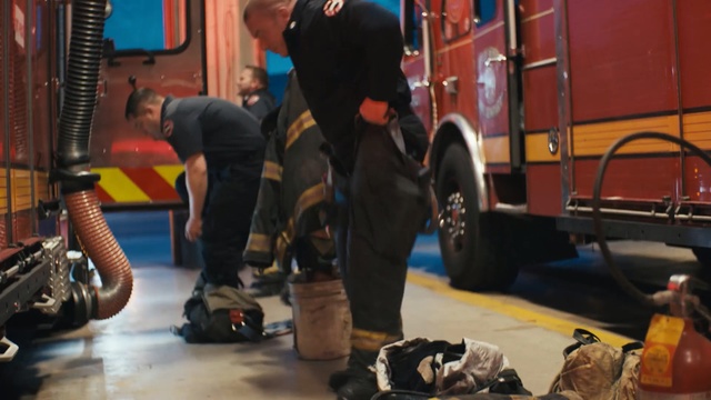 Video Reference N0: Fire department, Firefighter, Emergency service, Snout, Fire apparatus, Vehicle, Emergency vehicle, Personal protective equipment, Rescue, Service, Person, Man, Sitting, Child, Luggage, Young, Standing, Front, Table, Suitcase, Woman, Girl, Bag, Little, Black, Holding, Suit, Room, Riding, Bus, Computer, Parked, Phone, People, Group
