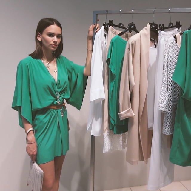 Video Reference N8: Clothing, Green, Dress, Turquoise, Shoulder, Fashion, Fashion design, Room, Sleeve, Boutique, Person, Indoor, Hanging, Standing, Wearing, Dressed, Clothes, Woman, Holding, Group, Large, White, Young, People, Man, Kitchen, Wall, Clothes hanger, Coat, Closet, Handbag, Skirt, Day dress, One-piece garment, Outerwear, Mantle, Robe, Costume design, Pattern (fashion design), Dry cleaning, Blouse, Mannequin
