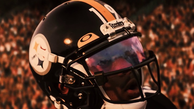 Video Reference N4: Helmet, Sports gear, Football gear, Football helmet, Football equipment, Personal protective equipment, Clothing, Sports equipment, Motorcycle helmet, American football, Headdress, Sitting, Black, Front, Close, Red, Motorcycle, Wearing, Man, Table, Standing, Player, Baseball, Ball, Goggles