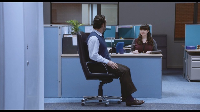 Video Reference N1: furniture, sitting, desk, standing, technology, electronic device, office chair, office, personal computer, chair, Person