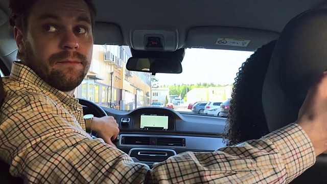 Video Reference N11: Vehicle, Driving, Car, Luxury vehicle, Automotive design, Steering wheel, Automotive exterior, Auto part, Mid-size car, Person, Man, Seat, Holding, Sitting, Truck, Bus, Looking, Front, Camera, Young, Cellphone, Phone, Woman, Smiling, Glasses, Wearing, Black, Shirt, Standing, Dog, Video, Riding, Land vehicle, Mirror, Automotive mirror, Rear-view mirror, Head restraint, Vehicle door, Windshield, Car seat