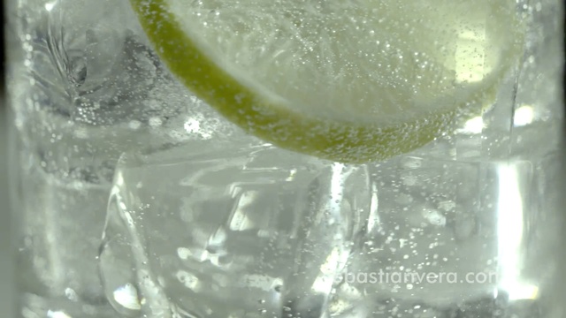 Video Reference N6: Gin and tonic, Lime, Drink, Lemon-lime, Vodka and tonic, Ice cube, Transparent material, Glass, Citrus, Lemonade, Person, Beverage, Food, Sitting, Table, Water, Small, Laying, Riding, Close, Orange, Dog, Yellow, Clear, White, Wave, Vase, Red, Soft drink, Lemon, Fluid, Liquid, Alcohol, Drinking water