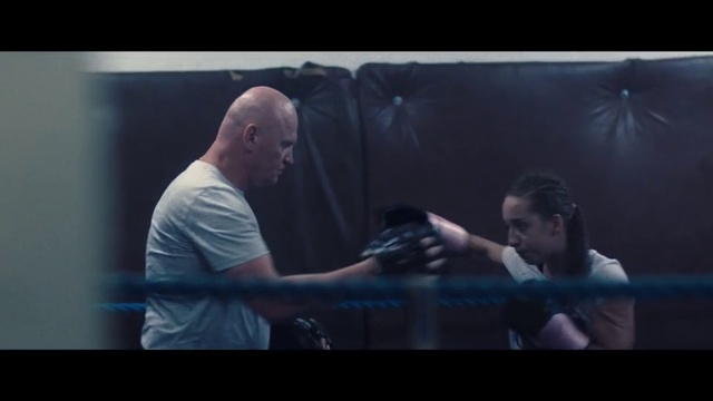 Video Reference N6: Boxing ring, Sport venue, Boxing, Scene, Interaction, Conversation, Striking combat sports, Contact sport, Screenshot, Darkness, Person, Man, Indoor, Looking, Playing, Window, Holding, Room, Front, Sitting, Game, Monitor, Television, Using, Screen, Player, Video, Standing, Ball, Woman, Living, Young, Swinging, Blurry, Table, People, Human face, Sport, Clothing
