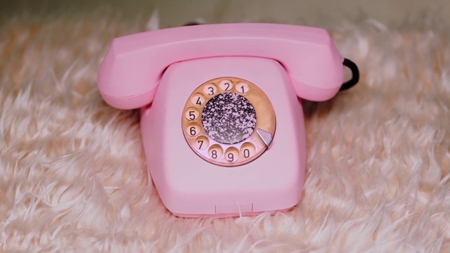 Video Reference N1: Pink, Product, Telephone, Corded phone, Telephony, Electronic device, Watch, Person, Indoor, Container, Sitting, Plastic, Cake, Table, Small, Basket, Box, Food, Filled, Remote, Little, White, Brush, Bowl, Plate, Cheese, Playing, Cloth