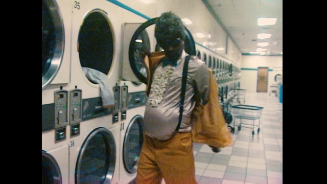 Video Reference N0: Laundry, Laundry room, Clothes dryer, Washing machine, Dry cleaning, Person, Indoor, Man, Window, Standing, Front, Woman, Mirror, Young, Bus, Kitchen, Holding, Black, Wearing, Dryer, Table, White, Sink, Computer, Luggage, Umbrella, Phone, Room, Suitcase, Board, Train, Appliance, White goods, Bathroom, Washer