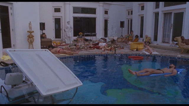 Video Reference N0: Swimming pool, Property, Leisure, Leisure centre, Building, Indoor, Table, Window, Counter, Food, Water, Sitting, Sink, Kitchen, Woman, Room, Plate, Man, Bowl, Vase, Large, Blue, White, Cake, Living, Standing, Holding, People, Group, Swimming, Pool, Cluttered