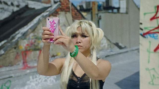 Video Reference N5: Blond, Snapshot, Pink, Water, Fun, Long hair, Photography, Cosplay, Costume, Person, Building, Outdoor, Young, Little, Holding, Sitting, Girl, Small, Front, Green, Street, Boy, Wearing, Food, Face, Table, Woman, Mouth, Standing, Walking, White, Eating, Human face, Clothing, Fashion accessory