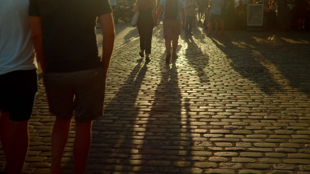 Video Reference N3: Cobblestone, Water, Shadow, Light, Morning, Sunlight, Flooring, Street, Leg, Road surface, Person, Outdoor, Building, Woman, Umbrella, Standing, Walking, People, Sidewalk, Holding, Rain, Man, Group, Wet, Young, Track, Brick, City, Train, Red, Ground, Clothing, Footwear, Way