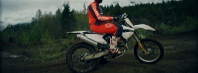 Video Reference N1: Land vehicle, Vehicle, Motorcycle, Motocross, Motorcycling, Freestyle motocross, Motorcycle racing, Motorsport, Endurocross, Enduro, Outdoor, Grass, Bicycle, Riding, Road, Rider, Helmet, Man, Wearing, Dirt, Red, Parked, Field, Sitting, Young, Country, Doing, Jumping, Green, Black, White, Standing, Yellow, Grassy, Air, Street, Tree, Wheel, Motorbike, Bike, Tire, Auto part