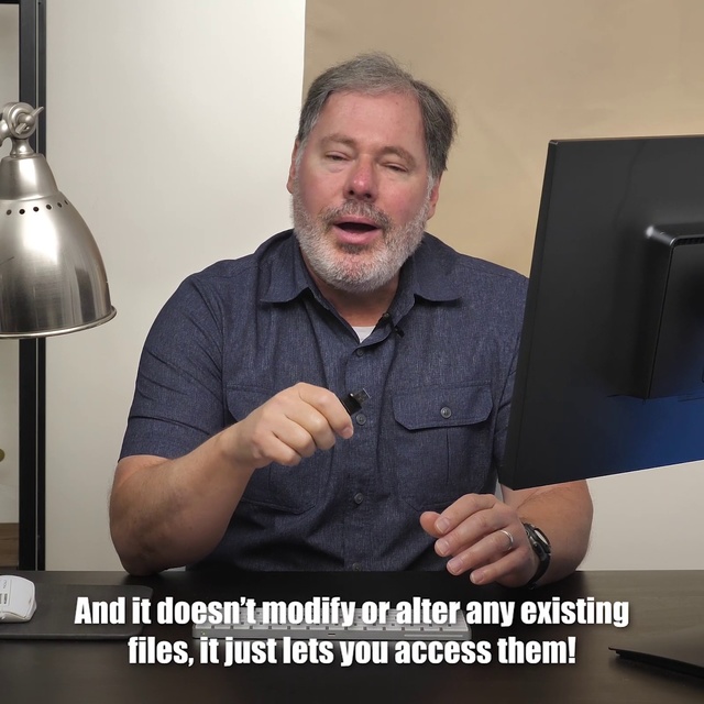 Video Reference N1: Arm, Finger, Muscle, Hand, Gesture, Photo caption, Photography, Job, Electronic device, Facial hair, Person, Man, Indoor, Holding, Photo, Sitting, Table, Posing, Black, Front, Smiling, Computer, Suit, Male, Wearing, Monitor, Laptop, Desk, Standing, Large, Sign, White, Remote, Wall, Text, Human face, Clothing, Screenshot