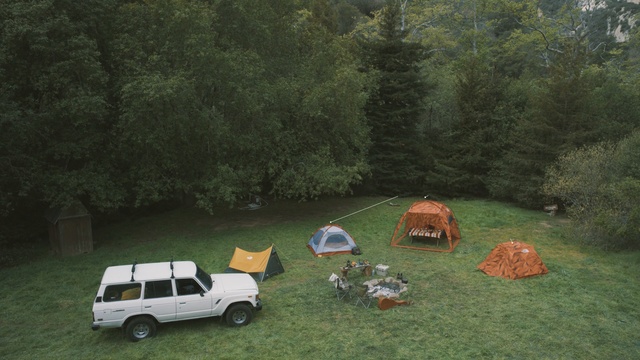 Video Reference N1: car, camping, wilderness, vehicle, grass, tree, plant, landscape, rural area, motor vehicle