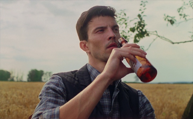 Video Reference N1: Drinking, Drink, Woodwind instrument, Person, Outdoor, Grass, Man, Food, Field, Holding, Eating, Young, Standing, Boy, Wearing, Large, Shirt, Close, Green, Baseball, Table, Grassy, Bat, Plate, Hot, Red, Water, White, Sky, Human face, Soft drink, Guy, Beard
