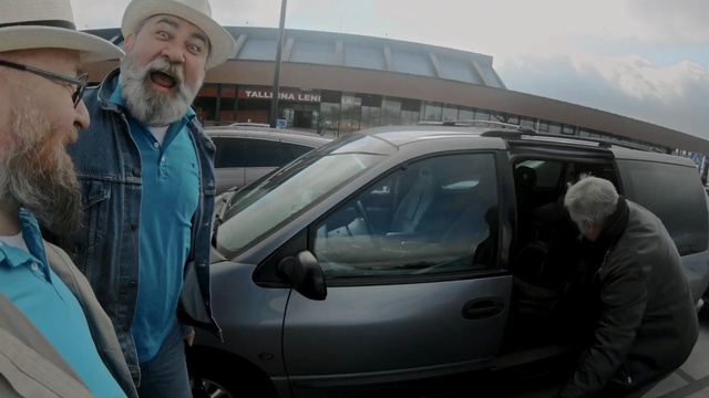 Video Reference N0: Motor vehicle, Vehicle, Car, Vehicle door, Automotive exterior, Automotive window part, Auto part, Windshield, Minivan, Person, Outdoor, Man, Building, Standing, Truck, Holding, Woman, Parking, Wearing, Hat, White, People, Talking, Walking, Street, Parked, Umbrella, Land vehicle, Wheel