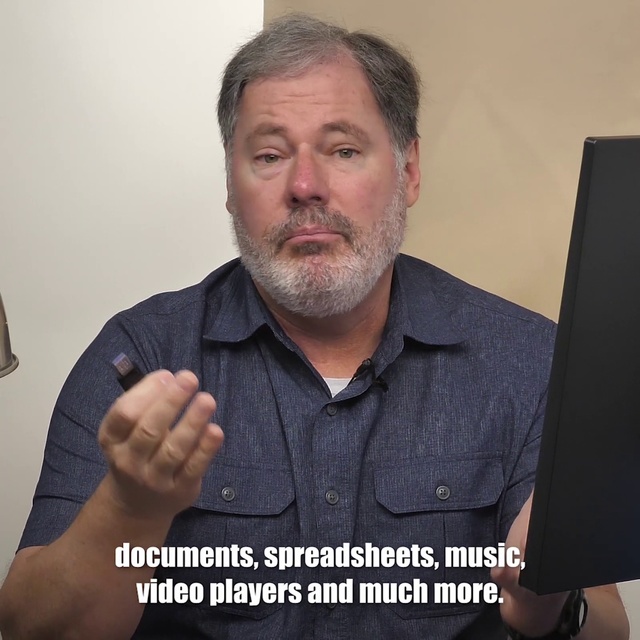 Video Reference N4: Facial hair, Chin, Finger, Forehead, Gesture, Moustache, Beard, Hand, Photo caption, Thumb, Person, Man, Indoor, Holding, Sitting, Looking, Front, Computer, Laptop, Black, Table, Posing, Smiling, Young, Sign, Phone, Wearing, Standing, Shirt, Wall, Human face, Text, Clothing, Screenshot, Human beard