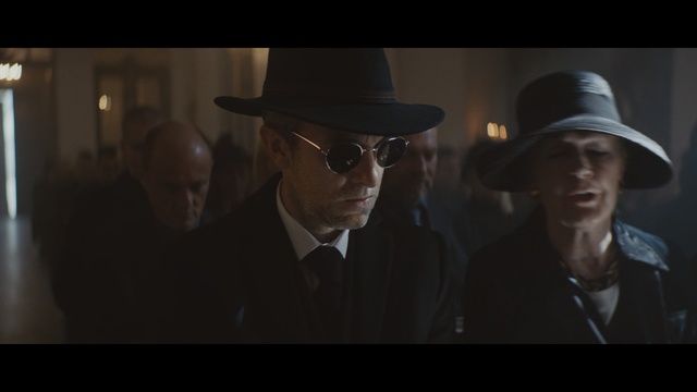 Video Reference N0: Fedora, Movie, Hat, Gentleman, Headgear, Darkness, Fashion accessory, Eyewear, Screenshot, Cowboy hat, Man, Person, Indoor, Clothing, Wearing, Photo, Looking, Suit, Front, Sitting, Standing, Table, Black, Woman, Dark, White, Holding, Wedding, People, Room, Human face, Glasses, Sun hat