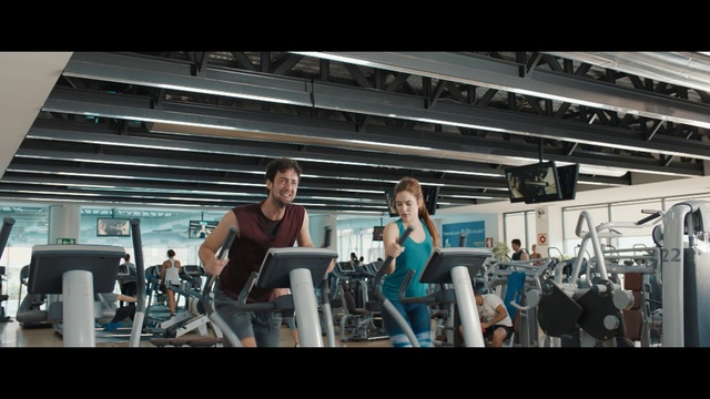 Video Reference N1: Gym, Shoulder, Physical fitness, Sport venue, Arm, Room, Muscle, Treadmill, Bodybuilding, Weight training, Man, Woman, Standing, Front, Table, People, Young, Holding, Group, Doing, Board, Air, Playing, Court, Kitchen, White, Person, Clothing, Computer, Laptop