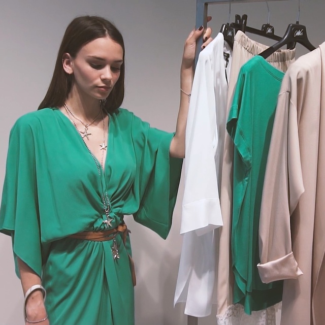 Video Reference N7: Clothing, Green, Turquoise, Dress, Robe, Fashion, Fashion design, Room, Outerwear, Boutique, Person, Indoor, Standing, Woman, Man, Wearing, Group, Photo, Posing, People, Holding, Clothes, Dressed, Hanging, White, Umbrella, Young, Large, Clothes hanger, Closet