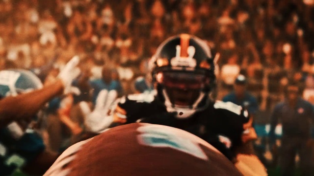 Video Reference N2: Helmet, Crowd, Sports gear, Personal protective equipment, American football, Audience, Event, Football equipment, Competition event, Football gear, Person, Man, Player, Game, Front, Holding, Ball, Standing, Swinging, Close, Large, People, Playing, Baseball, White, Woman, Red, Court, Room, Bat, Sports equipment, Football helmet, Clothing, Human face