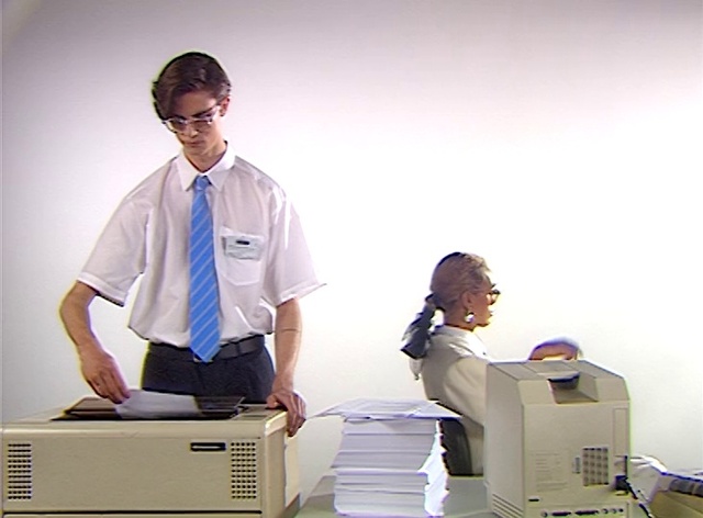 Video Reference N3: Glasses, Sleeve, Standing, Gesture, Dress shirt, Office equipment, Medical equipment, Tie, Output device, Office supplies